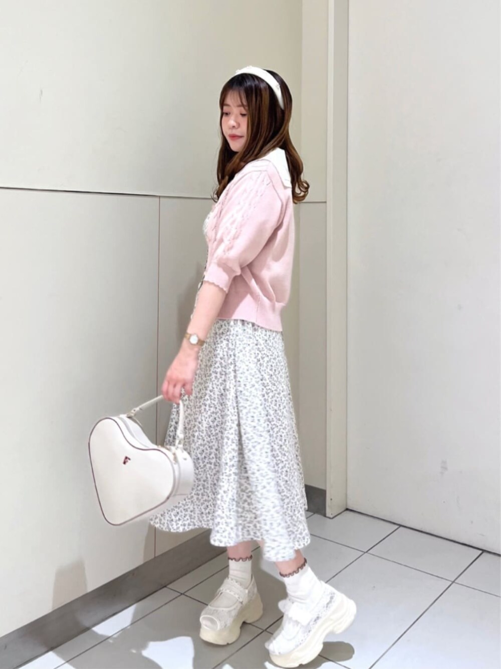 ホワイト系のハンドバッグ、ホワイト系のサンダル、ピンク系のカーディガン/ボレロを着用したレディースの夏コーディネートの2枚目の写真