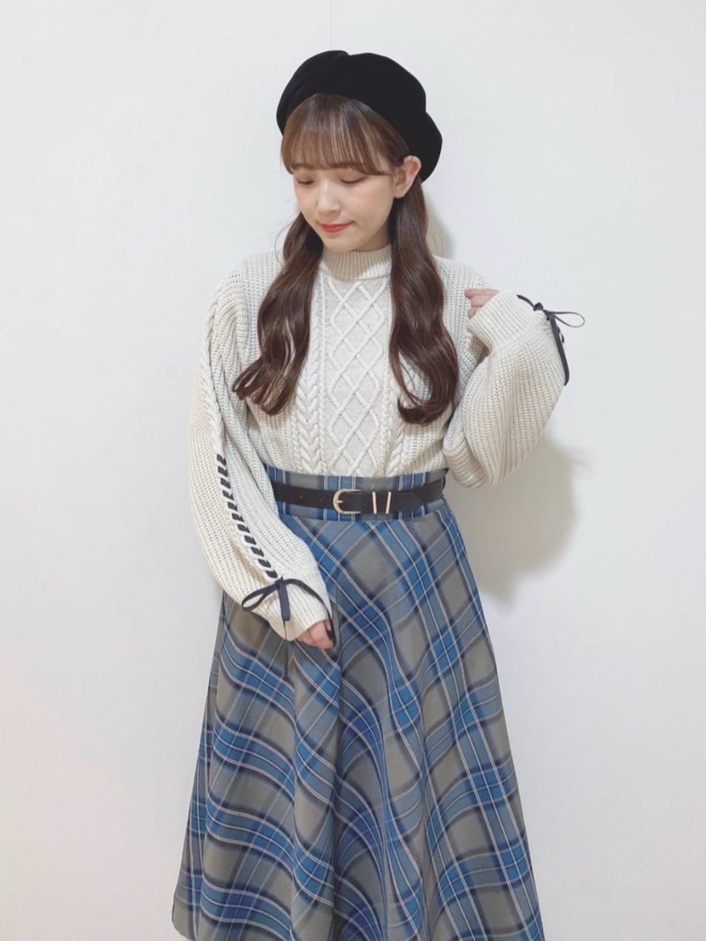 ブルー系のスカート、ホワイト系のニット/セーター、ブラック系のブーツを着用したレディースの冬コーディネートの2枚目の写真