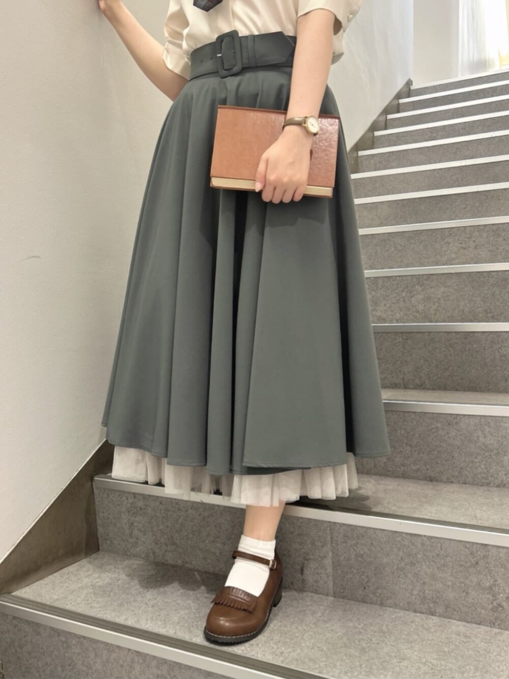 ブラウン系のローファー、グリーン系のスカート、ホワイト系のTシャツ/カットソーを着用したレディースの夏コーディネートの3枚目の写真