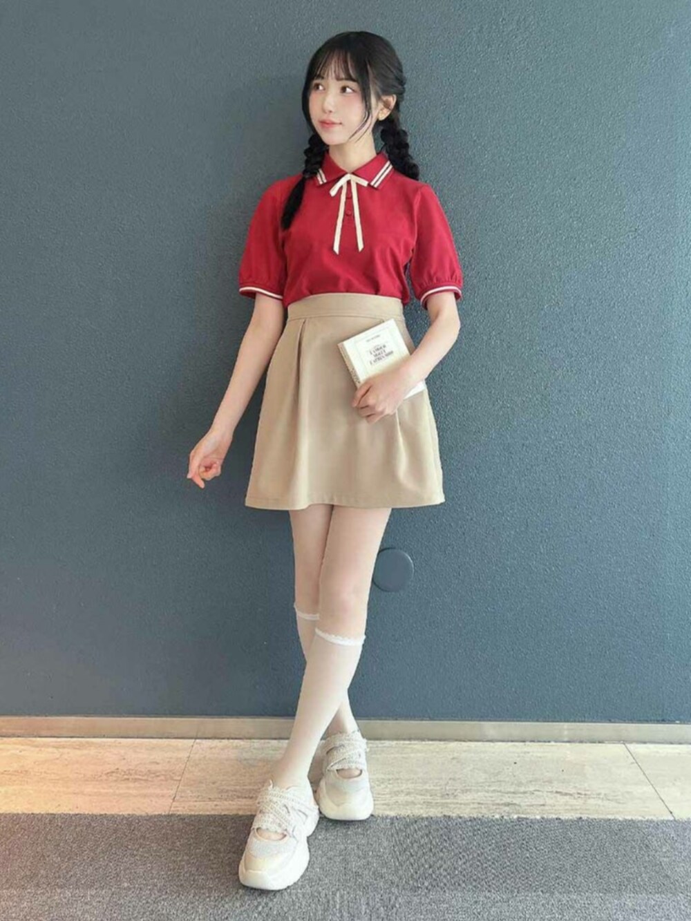 ベージュ系のスカート、レッド系のポロシャツを着用したレディースの春コーディネートの2枚目の写真