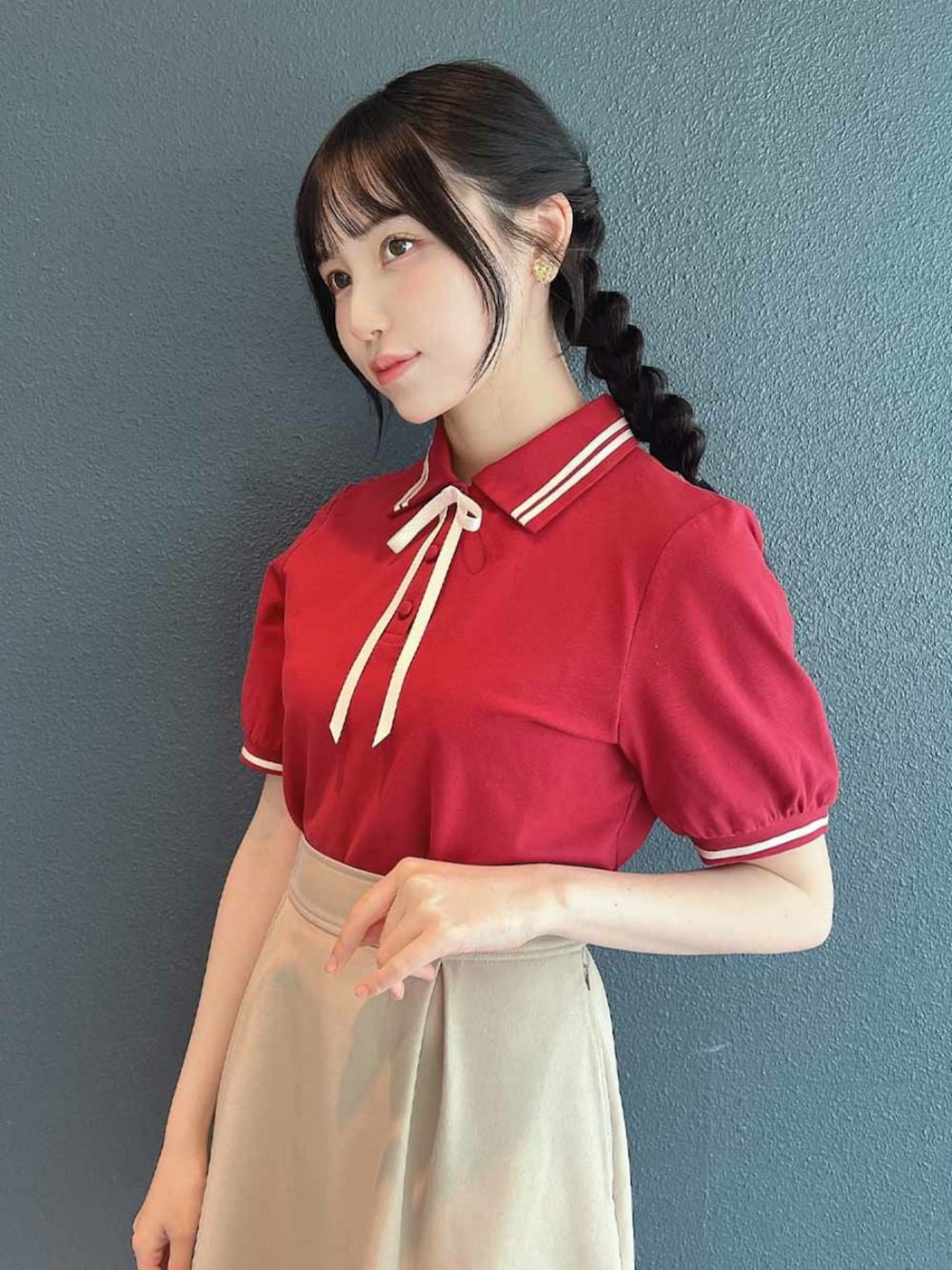 ホワイト系のスニーカー、ベージュ系のスカート、レッド系のポロシャツを着用したレディースの春コーディネートの3枚目の写真