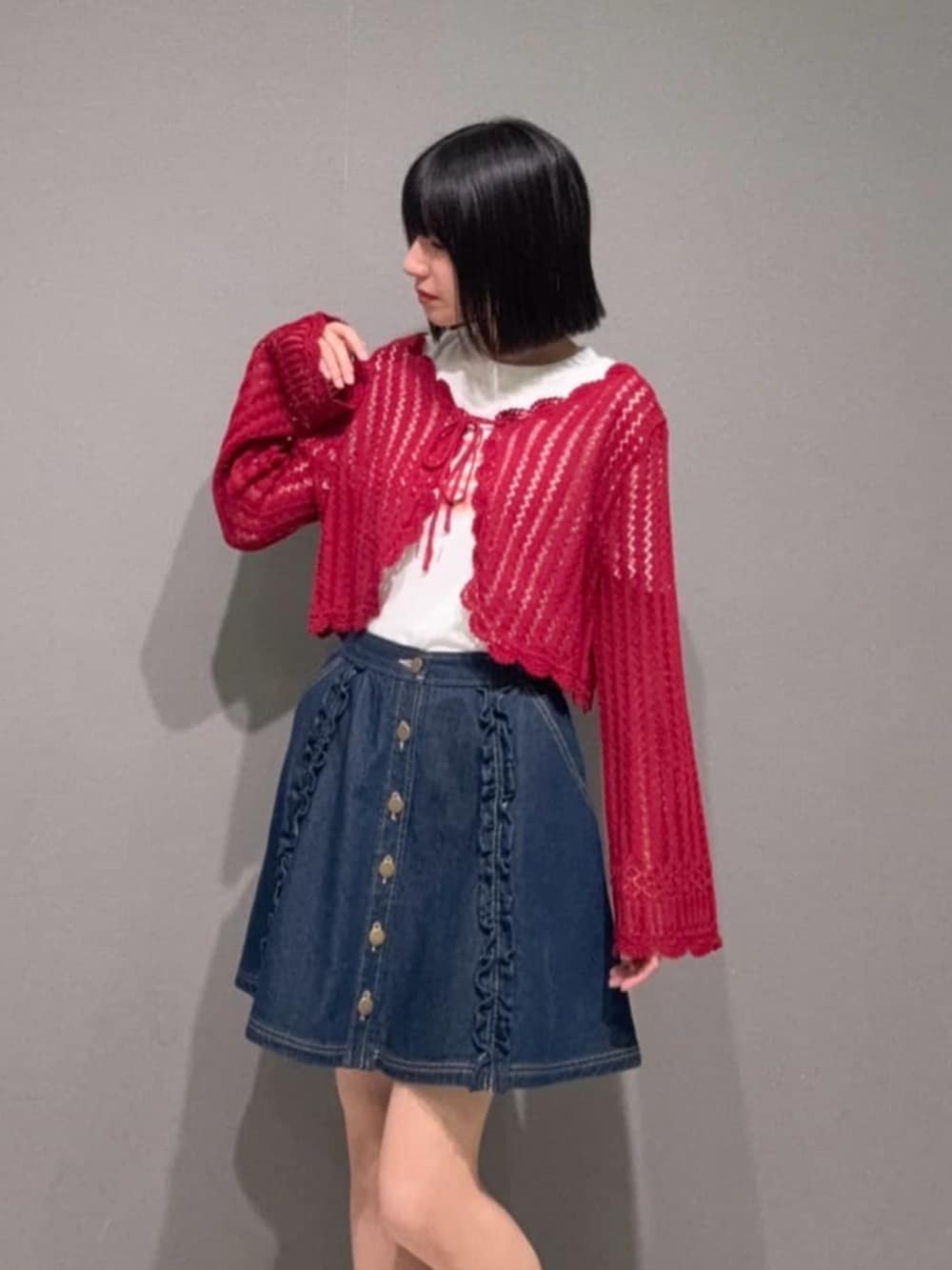 レッド系のパンプス、ブルー系のデニムスカート、レッド系のカーディガン/ボレロを着用したレディースの夏コーディネートの2枚目の写真