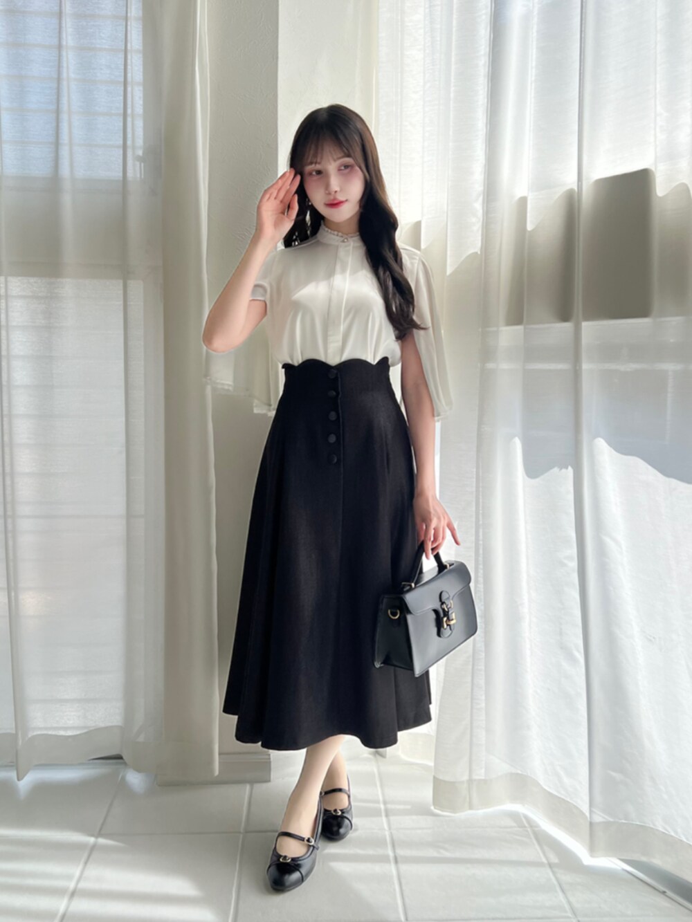 ブラック系のハンドバッグ、ブラック系のデニムスカート、ホワイト系のシャツ/ブラウスを着用したレディースの夏コーディネートの2枚目の写真