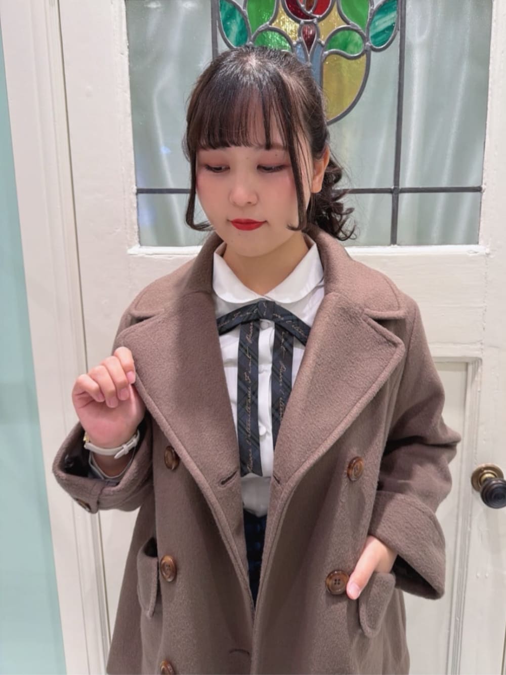 ブルー系のショルダーバッグ、ブラウン系のピーコート、ホワイト系のシャツ/ブラウスを着用したレディースの冬コーディネートの3枚目の写真