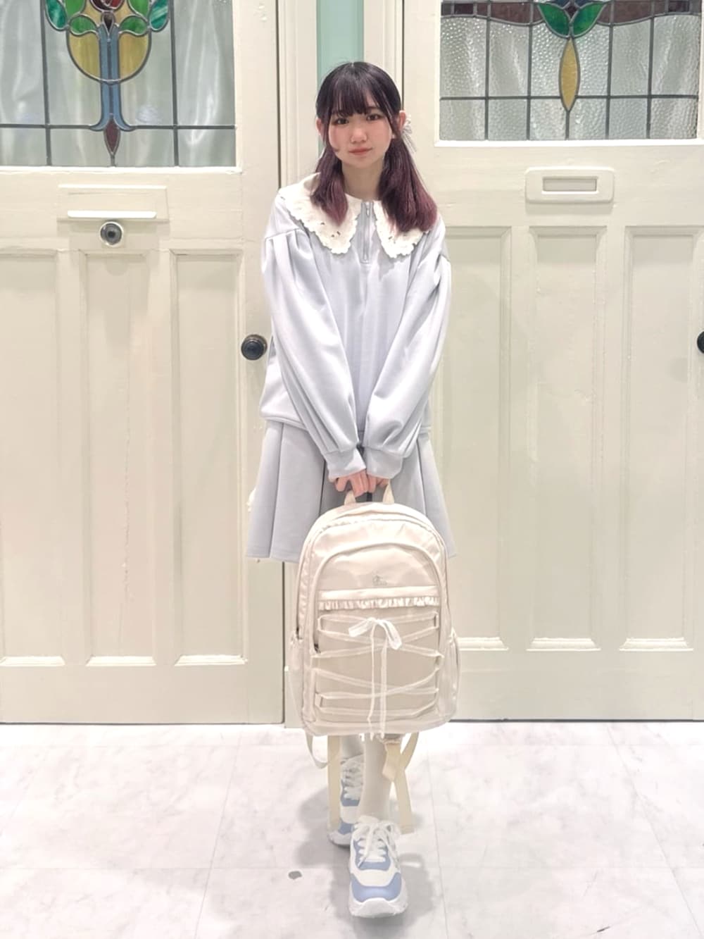 グレー系のスウェット、ホワイト系のバックパック/リュック、ブルー系のスカートを着用したレディースの春コーディネートの2枚目の写真