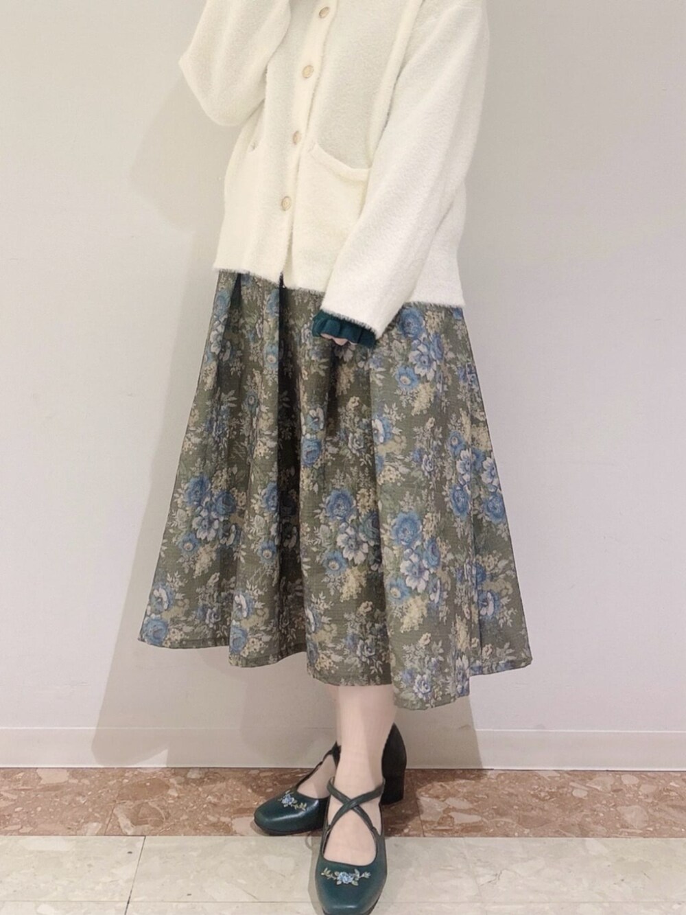 グリーン系のスカート、グリーン系のニット/セーター、ホワイト系のカーディガン/ボレロを着用したレディースの秋コーディネートの2枚目の写真