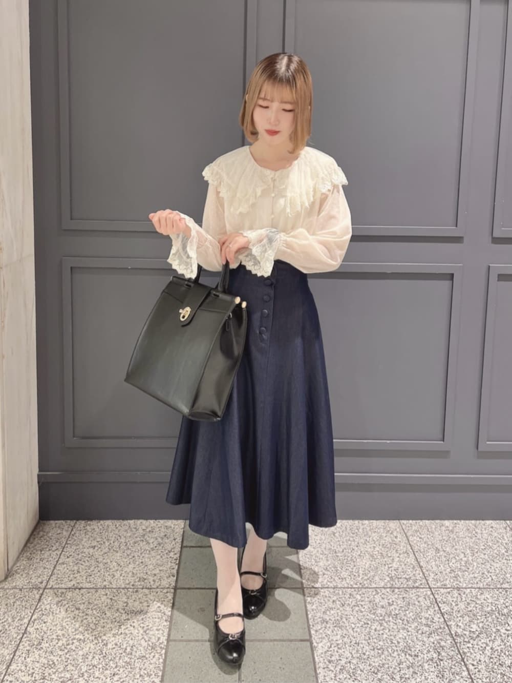 ブルー系のデニムスカート、ブラック系のパンプス、ブラック系のトートバッグを着用したレディースの秋コーディネートの2枚目の写真