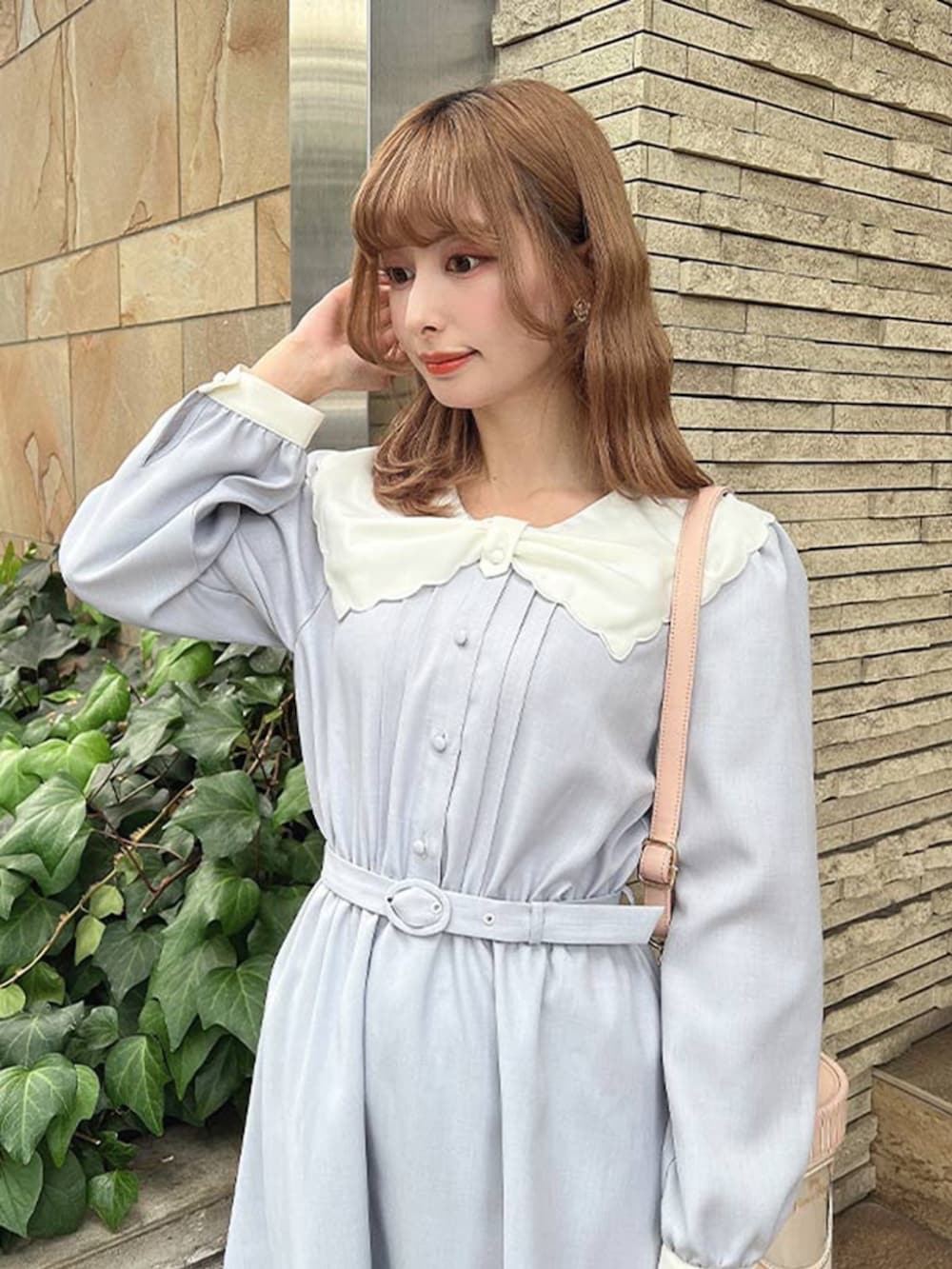 ホワイト系のパンプス、ピンク系のショルダーバッグ、ブルー系のワンピースを着用したレディースの冬コーディネートの2枚目の写真