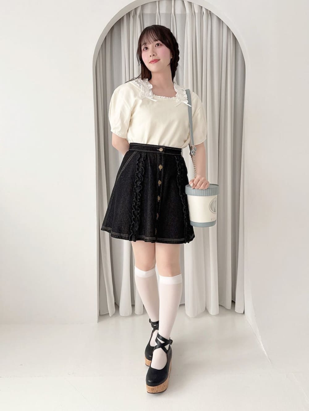 ブラック系のパンプス、ホワイト系のTシャツ/カットソー、ブラック系のデニムスカートを着用したレディースの夏コーディネートの2枚目の写真