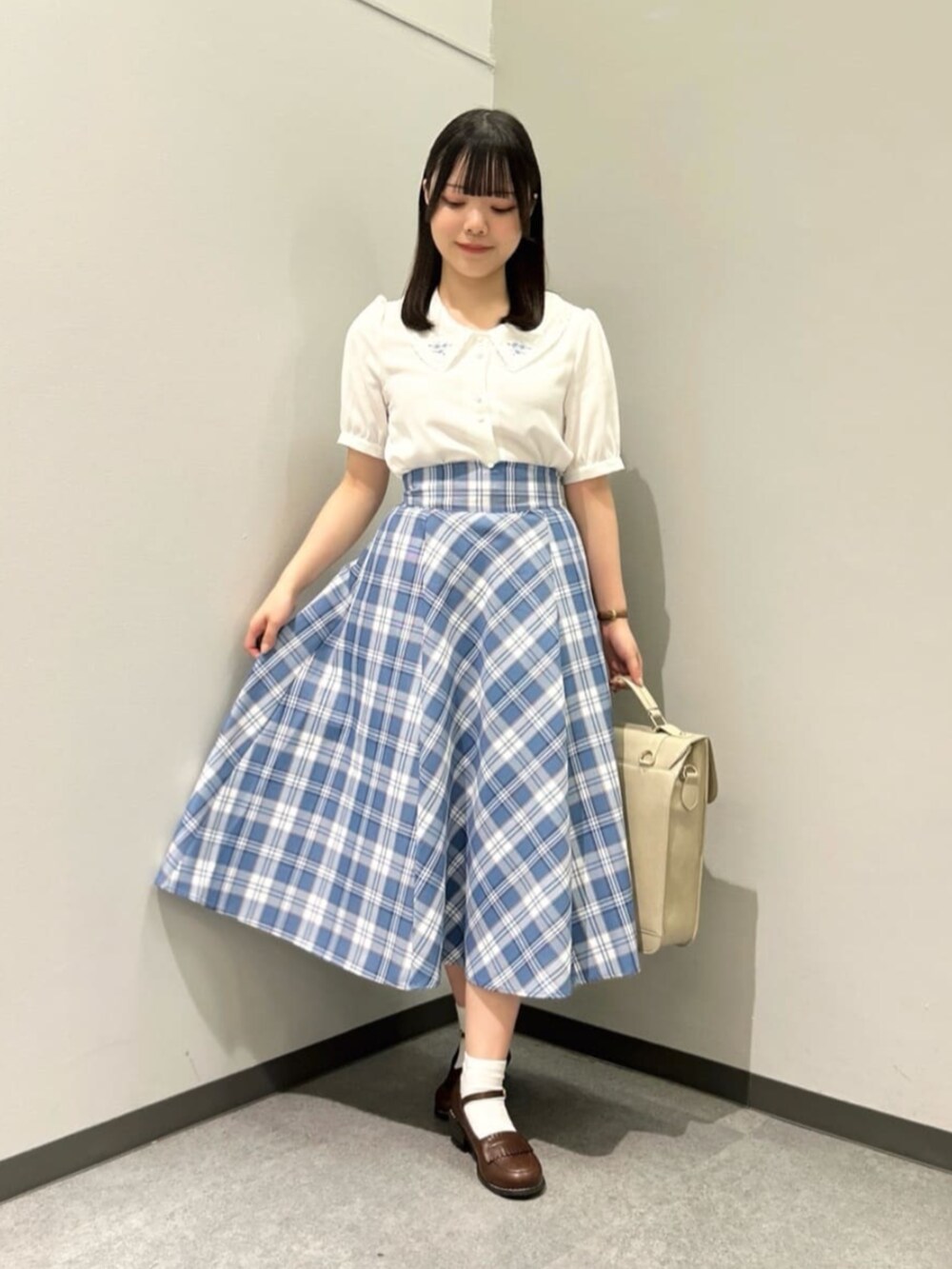 ベージュ系のハンドバッグ、ブラウン系のローファー、ホワイト系のカーディガン/ボレロを着用したレディースの春コーディネートの3枚目の写真