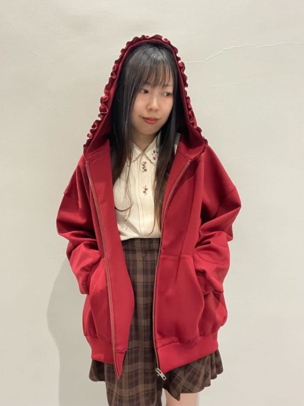 ブラウン系のスカート、レッド系のパーカー、ブラウン系のブーツを着用したレディースの秋コーディネートの3枚目の写真