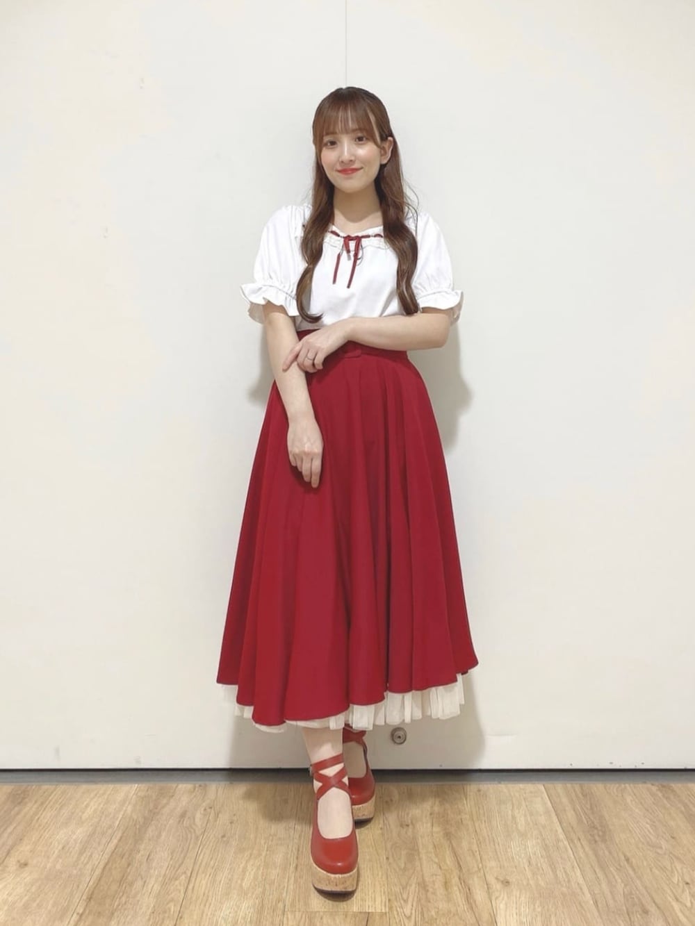 レッド系のパンプス、レッド系のハンドバッグ、レッド系のスカートを着用したレディースの夏コーディネートの2枚目の写真