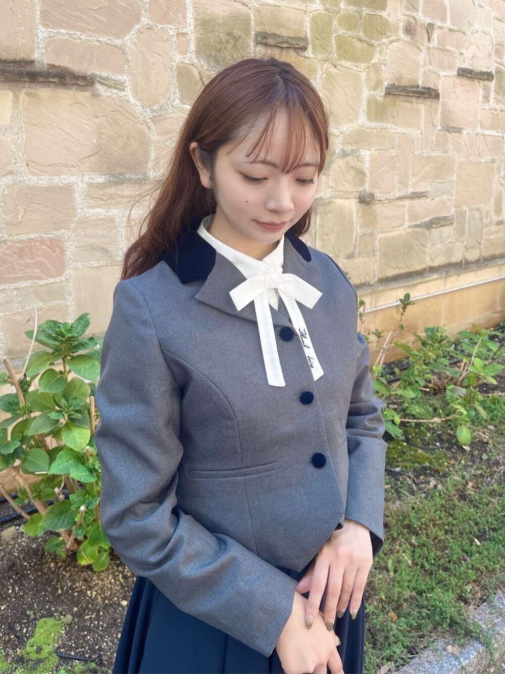 ピンク系のスカート、ブラック系のトートバッグ、ブラック系のパンプスを着用したレディースの秋コーディネートの2枚目の写真