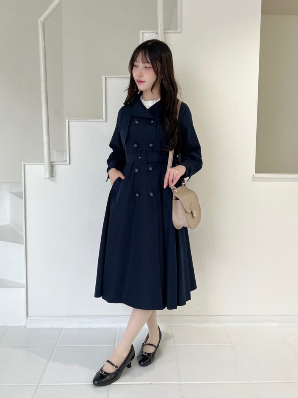 ブラック系のパンプス、ホワイト系のシャツ/ブラウス、ブルー系のトレンチコートを着用したレディースの秋コーディネートの2枚目の写真