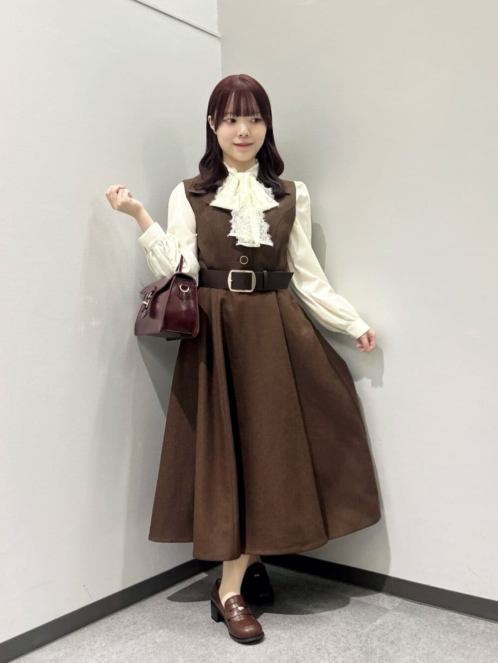 レッド系のハンドバッグ、ブラウン系のローファー、ホワイト系のシャツ/ブラウスを着用したレディースの秋コーディネートの4枚目の写真