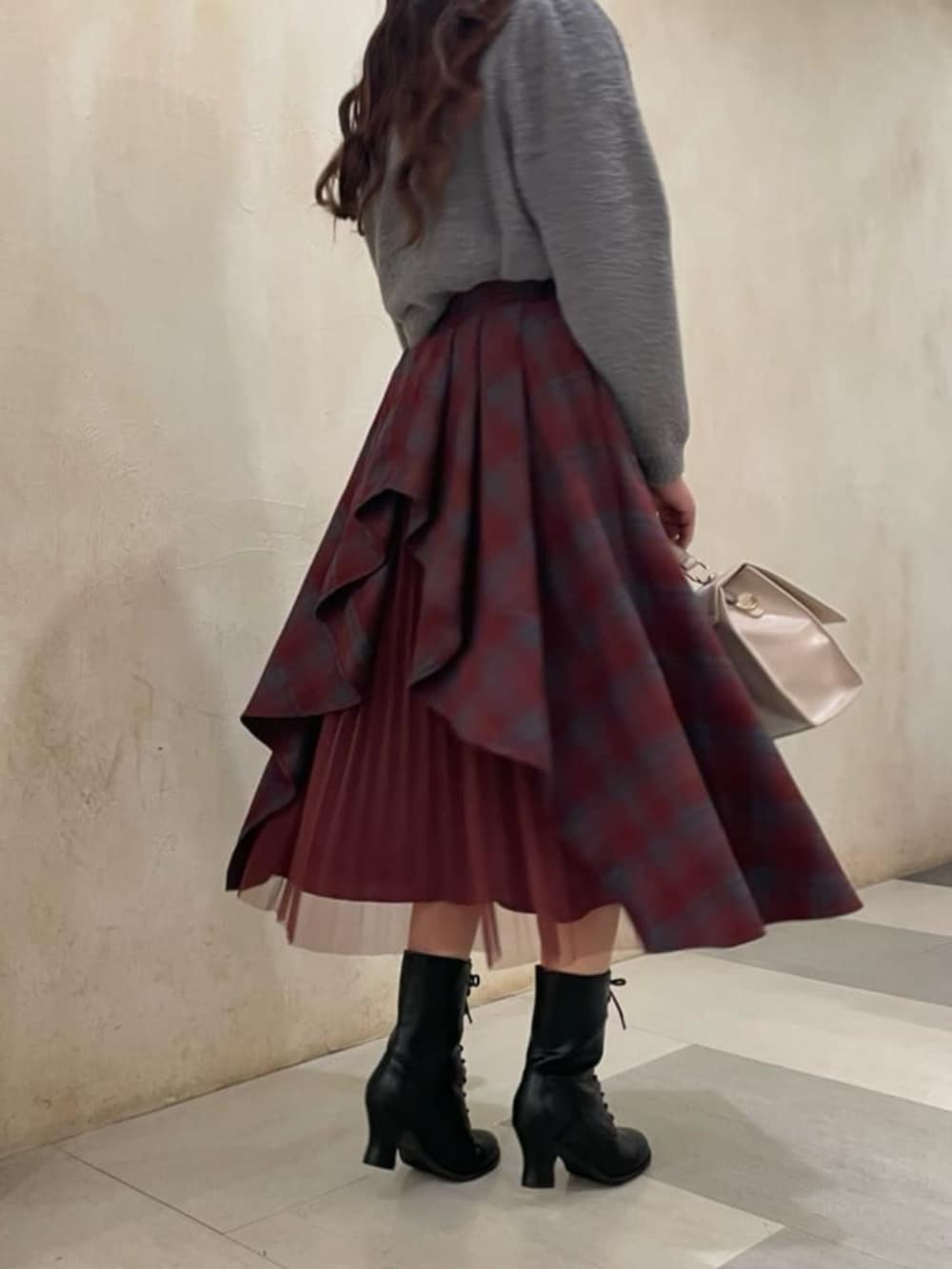 ブラック系のライダースジャケット、レッド系のスカート、グレー系のニット/セーターを着用したレディースの秋コーディネートの2枚目の写真