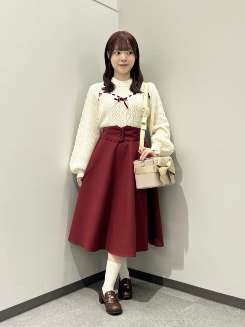 ブラウン系のローファー、レッド系のスカート、ホワイト系のニット/セーターを着用したレディースの秋コーディネートの2枚目の写真