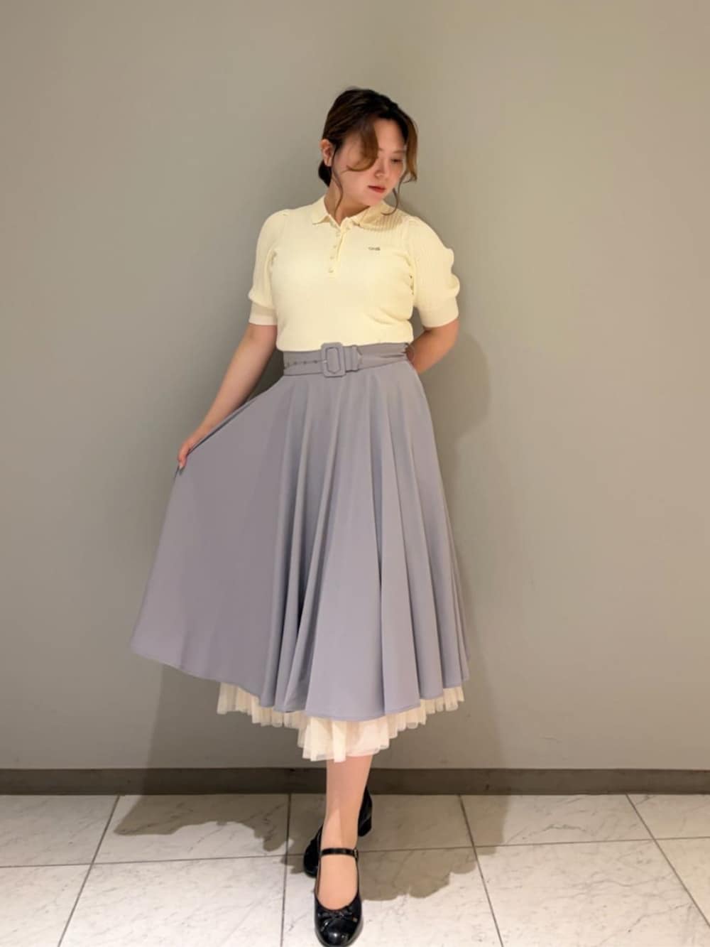 ブラック系のバレエシューズ、ホワイト系のポロシャツ、グレー系のスカートを着用したレディースの夏コーディネートの2枚目の写真