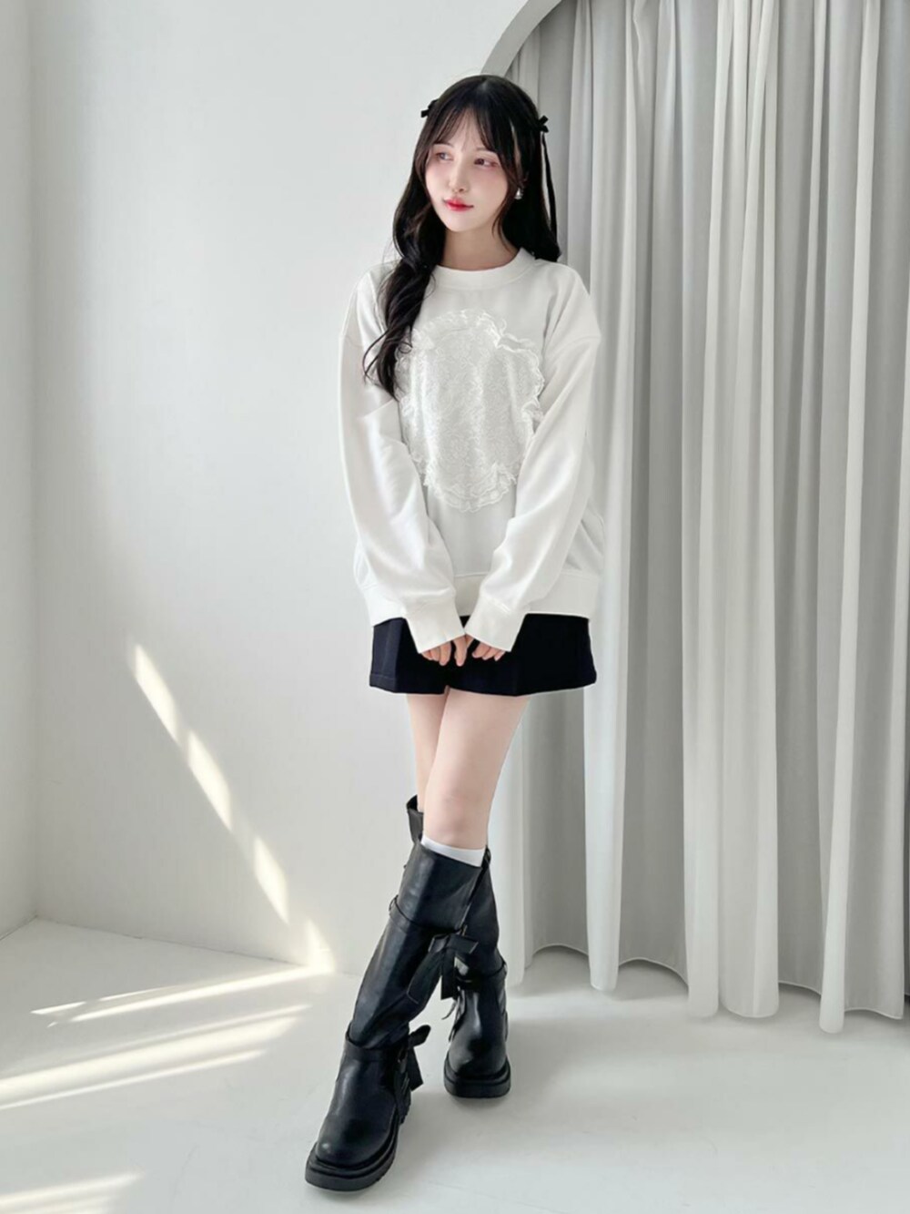 ブラック系のブーツ、ホワイト系のスウェット、ブラック系のその他パンツを着用したレディースの秋コーディネートの2枚目の写真