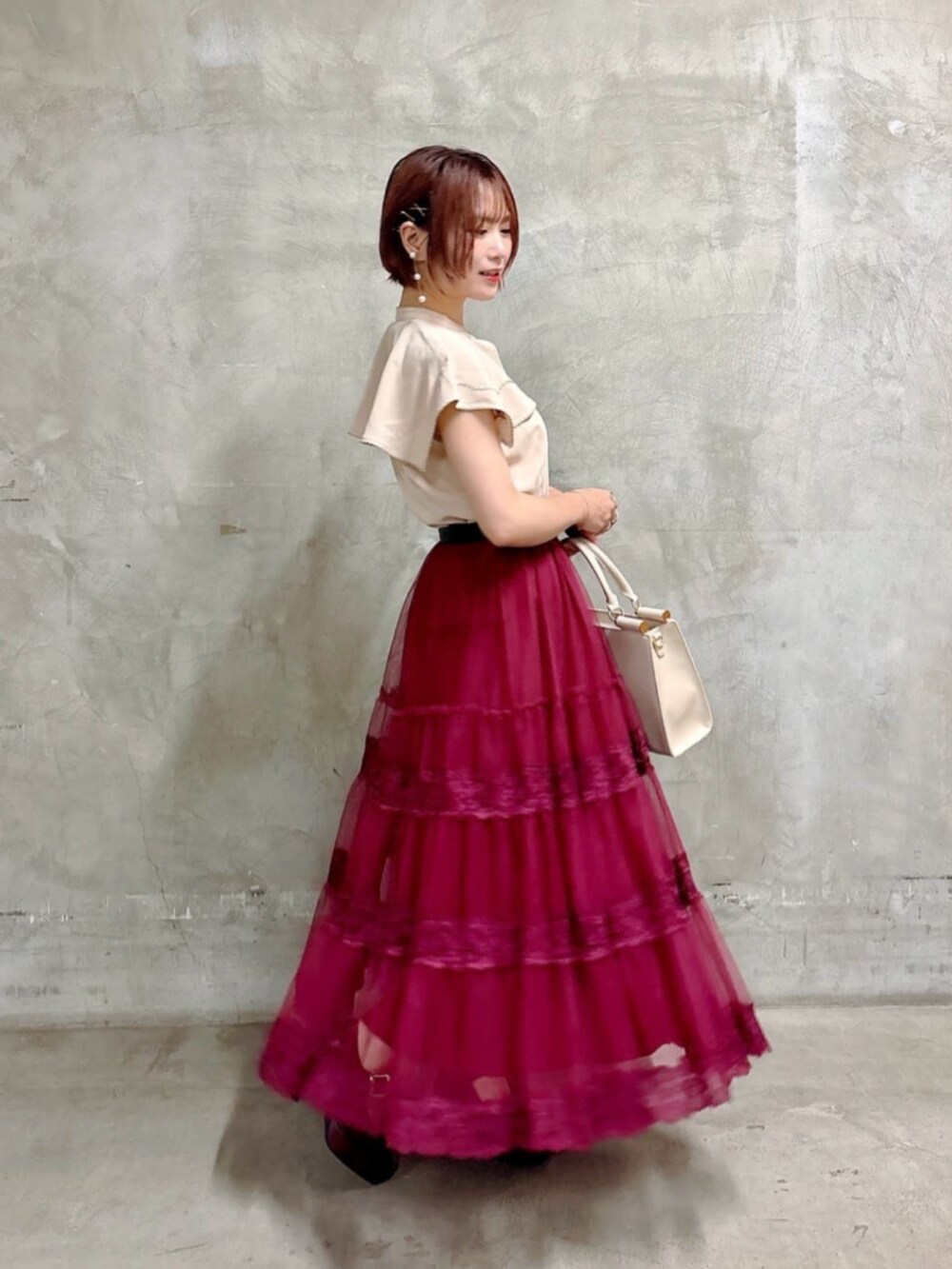 ブラウン系のパンプス、レッド系のスカート、ホワイト系のトートバッグを着用したレディースの夏コーディネートの3枚目の写真