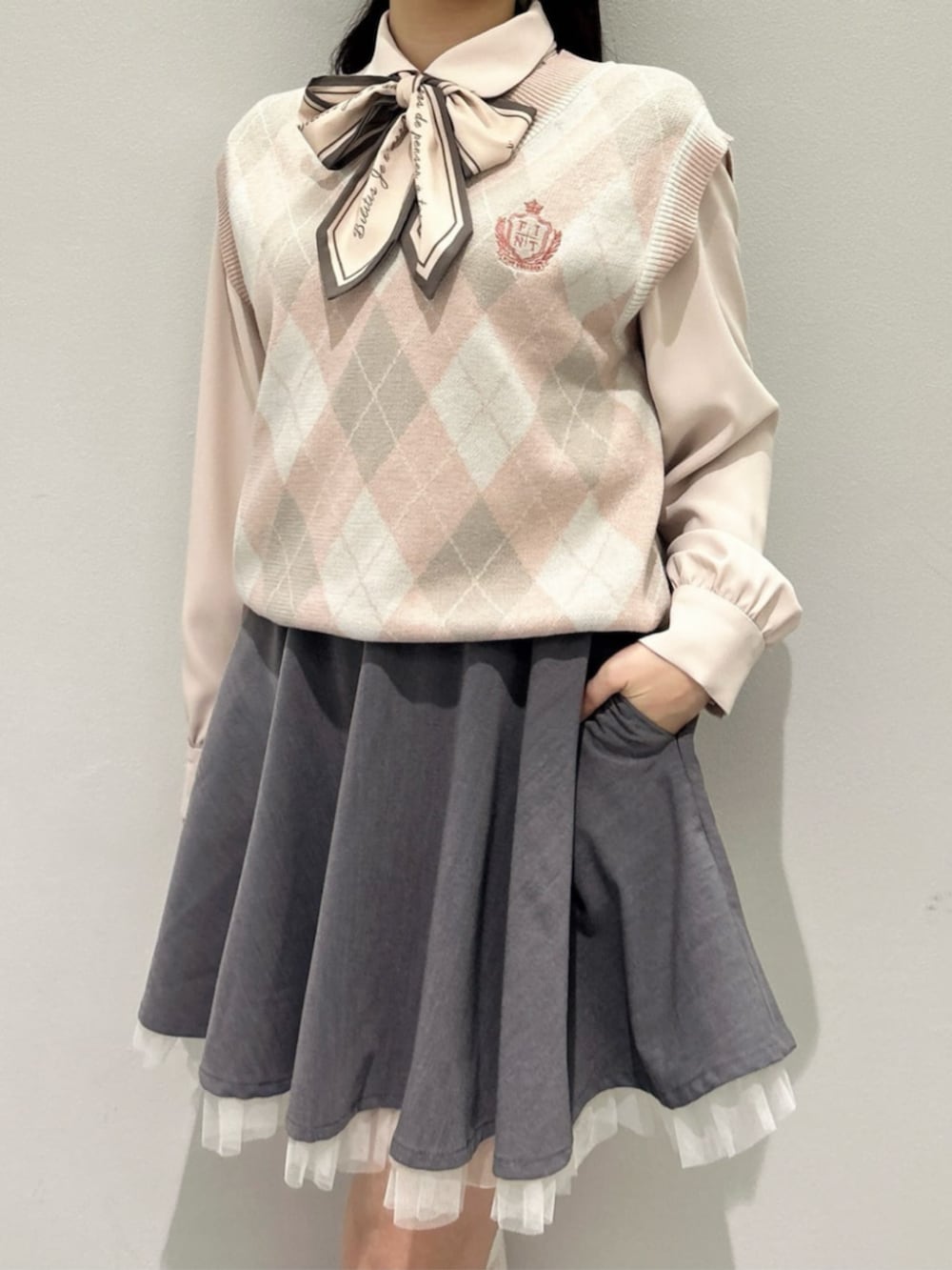 グレー系のスカート、ブラウン系のローファー、ピンク系のベストを着用したレディースの春コーディネートの3枚目の写真