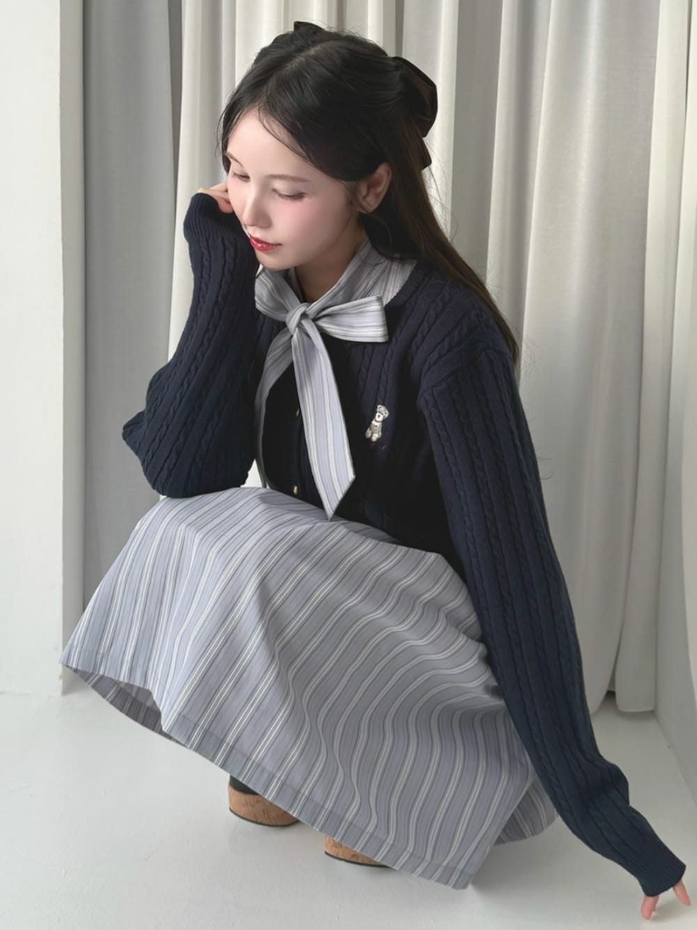 ブラック系のパンプス、ブルー系のカーディガン/ボレロを着用したレディースの冬コーディネートの2枚目の写真