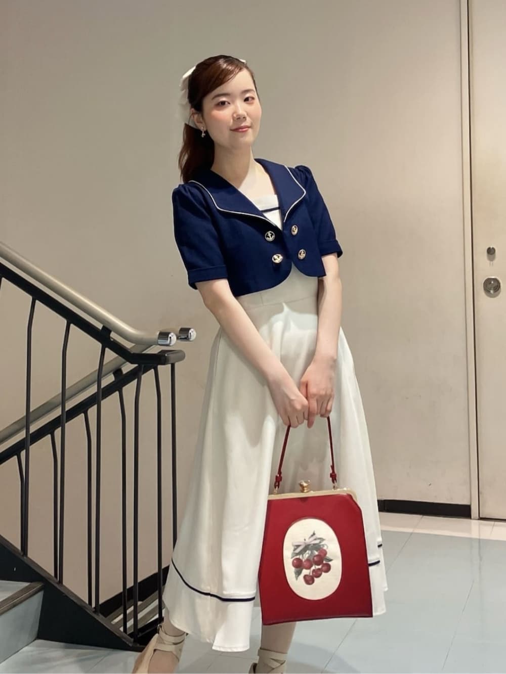 ホワイト系のパンプス、レッド系のハンドバッグ、ブルー系のジャンパースカートを着用したレディースの夏コーディネートの3枚目の写真