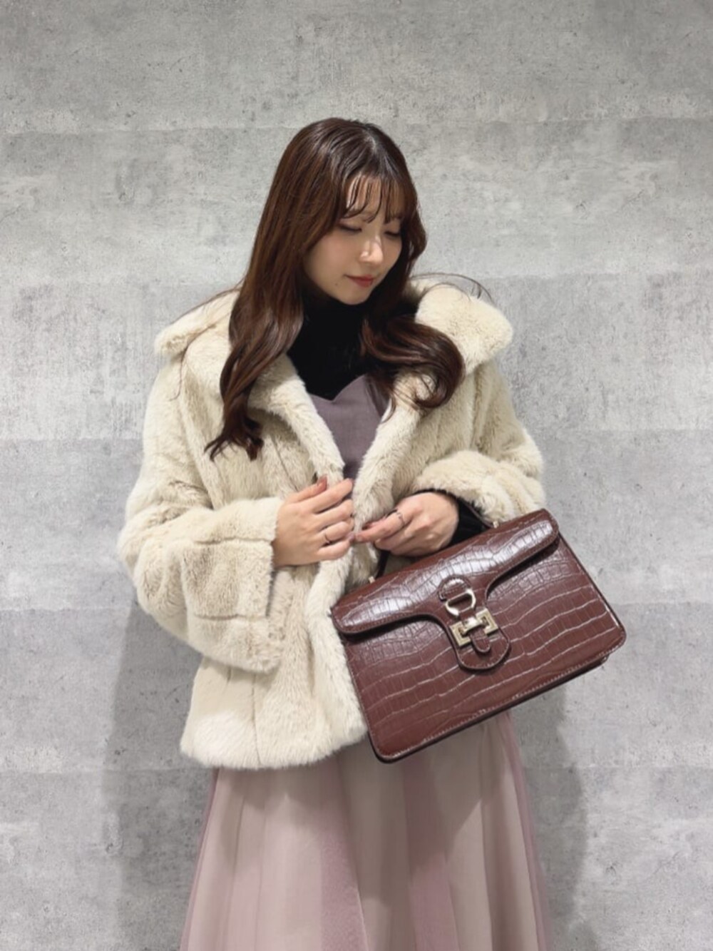 レッド系のパンプス、イエロー系のハンドバッグ、ブラック系のニット/セーターを着用したレディースの冬コーディネートの2枚目の写真