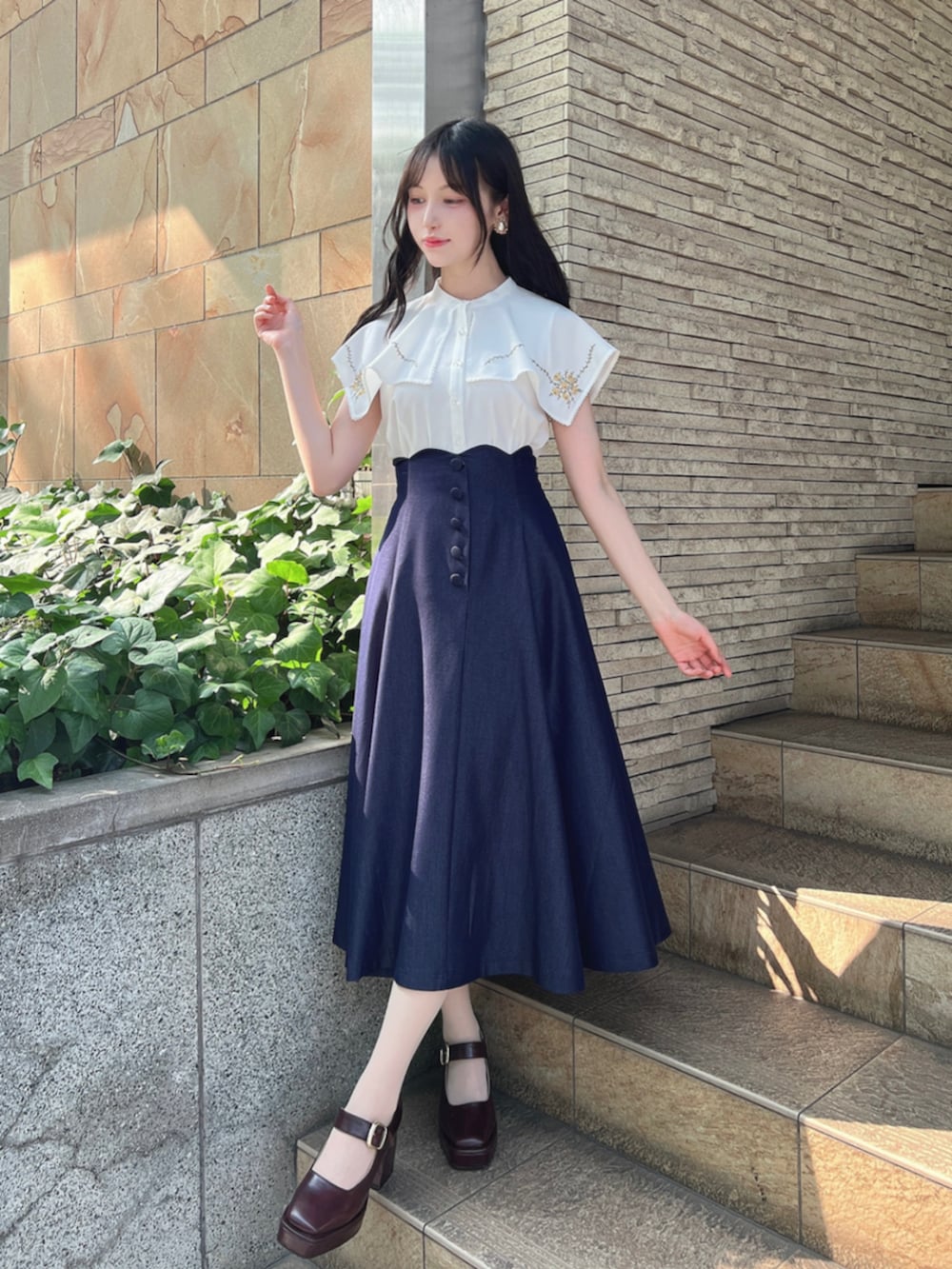 ブラウン系のパンプス、ホワイト系のシャツ/ブラウス、ブルー系のデニムスカートを着用したレディースの夏コーディネートの2枚目の写真