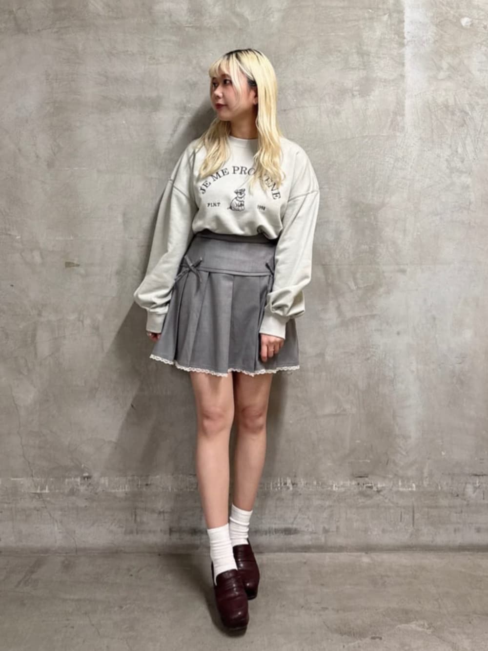 グレー系のスカート、グリーン系のスウェットを着用したレディースの春コーディネートの2枚目の写真