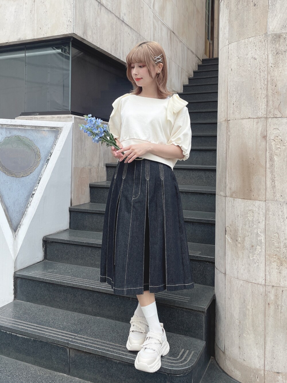 ホワイト系のスニーカー、ブラック系のデニムスカート、ホワイト系のTシャツ/カットソーを着用したレディースの春コーディネートの2枚目の写真