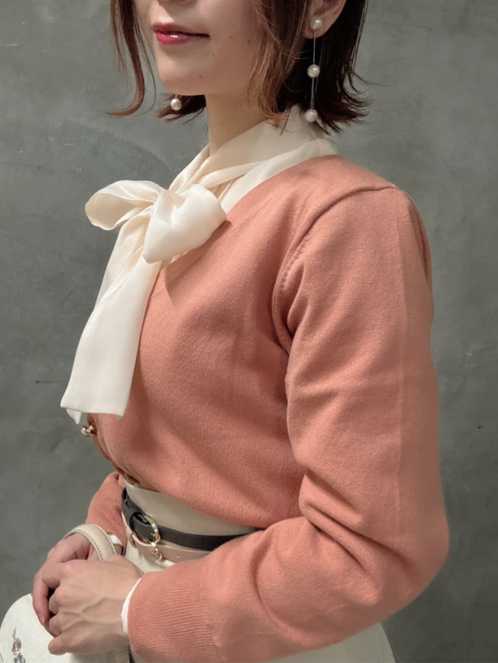 ピンク系のシャツ/ブラウス、ホワイト系のハンドバッグ、ベージュ系のスカートを着用したレディースの冬コーディネートの3枚目の写真