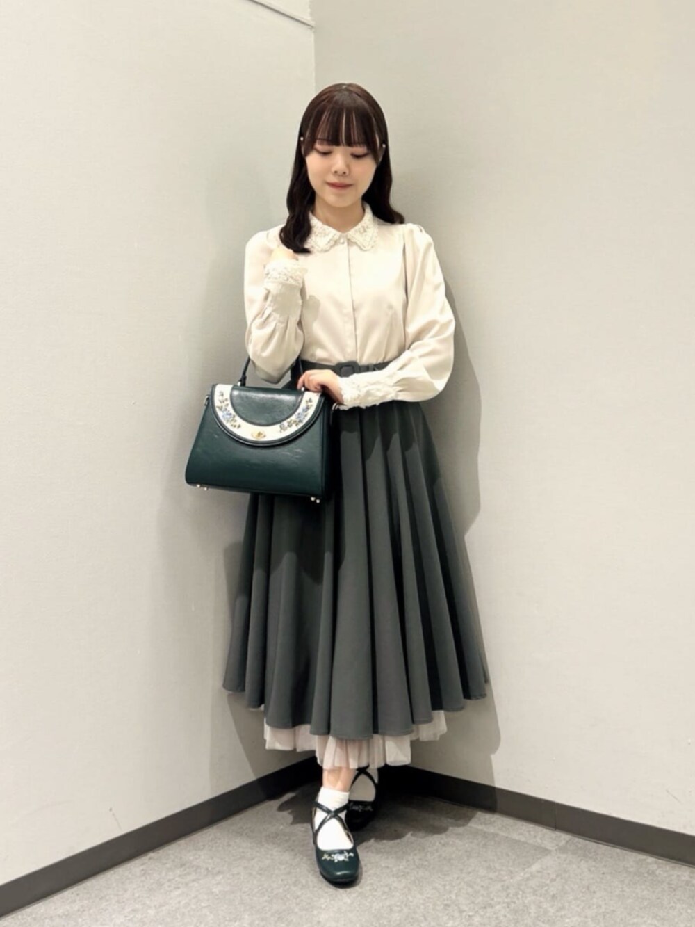 グリーン系のスカート、ピンク系のシャツ/ブラウス、ブルー系のハンドバッグを着用したレディースの秋コーディネートの2枚目の写真