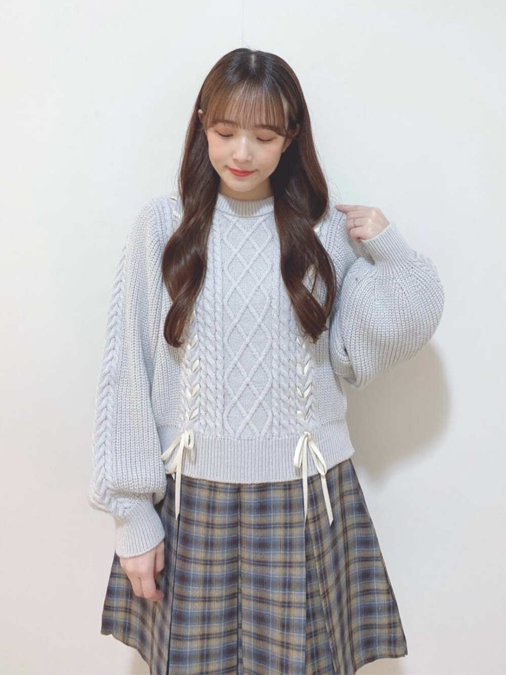 ベージュ系のスカート、グレー系のニット/セーター、ホワイト系のダウンジャケット/コートを着用したレディースの秋コーディネートの2枚目の写真