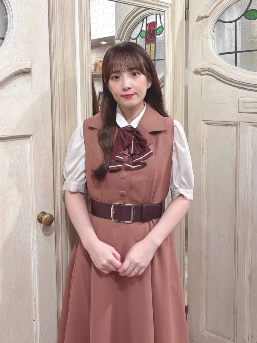 ブラウン系のパンプス、レッド系のワンピース、ベージュ系のシャツ/ブラウスを着用したレディースの秋コーディネートの2枚目の写真