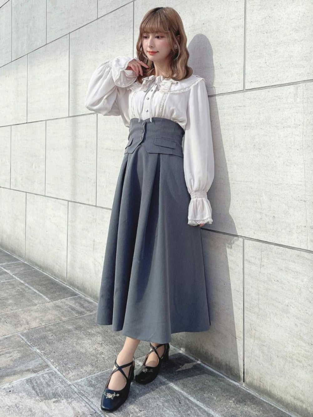 ブラック系のパンプス、ピンク系のシャツ/ブラウス、グレー系のスカートを着用したレディースの冬コーディネートの2枚目の写真