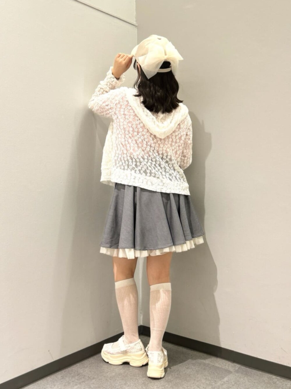 グレー系のスカート、ホワイト系のパーカー、ホワイト系のサンダルを着用したレディースの春コーディネートの2枚目の写真