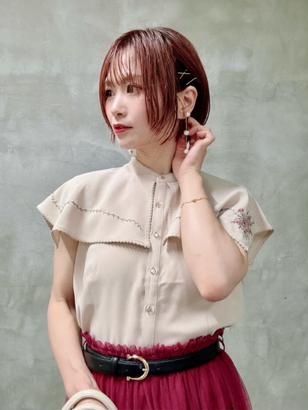 ブラウン系のパンプス、レッド系のスカート、ホワイト系のトートバッグを着用したレディースの夏コーディネートの2枚目の写真