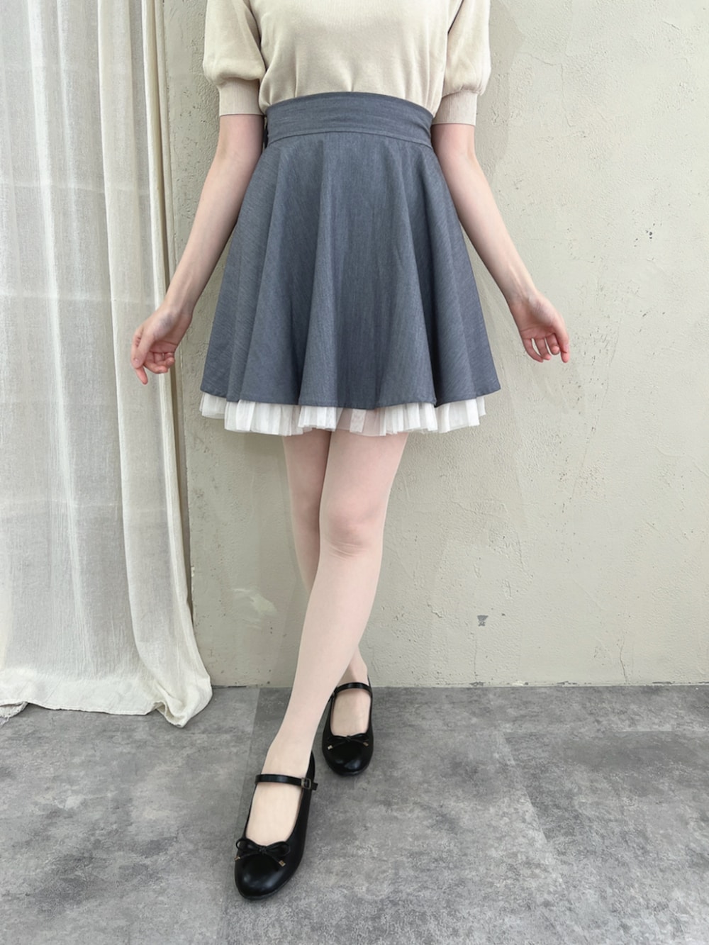 ブラック系のパンプス、グレー系のスカート、ホワイト系のニット/セーターを着用したレディースの夏コーディネートの3枚目の写真