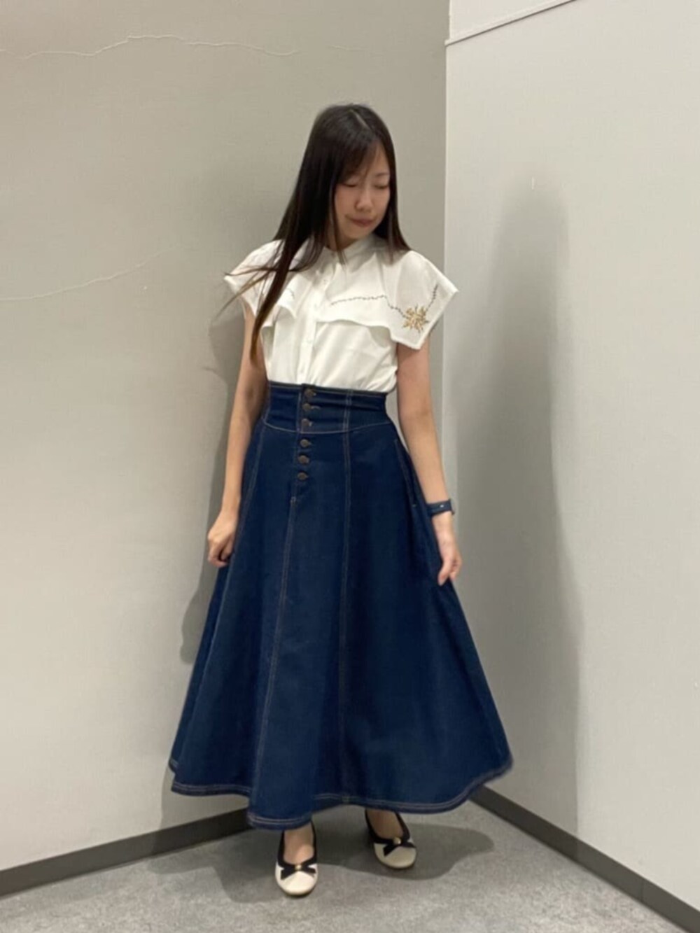 ホワイト系のパンプス、ホワイト系のシャツ/ブラウス、ブルー系のデニムスカートを着用したレディースの夏コーディネートの2枚目の写真