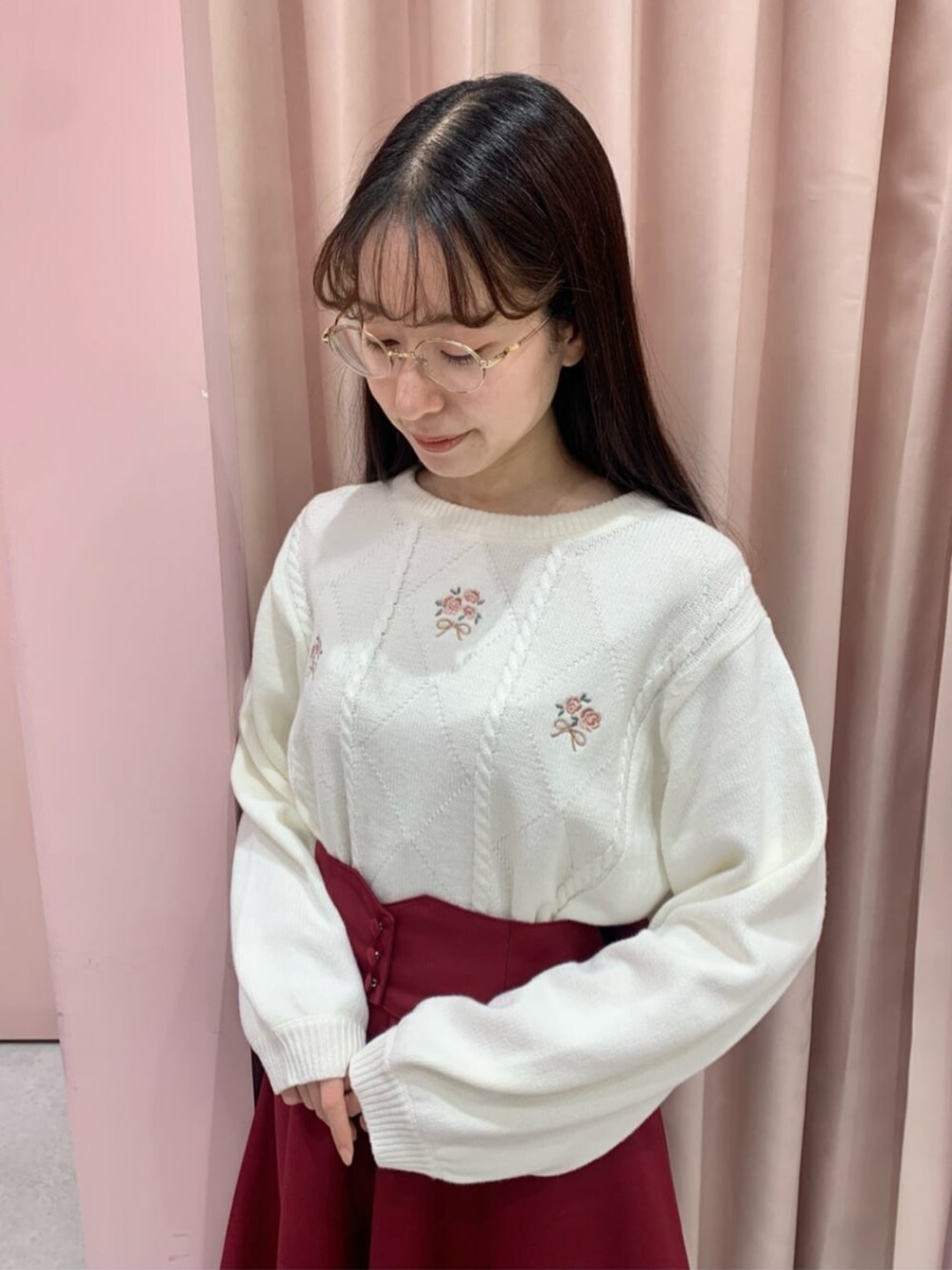 レッド系のスカート、ブラウン系のパンプス、ホワイト系のニット/セーターを着用したレディースの冬コーディネートの2枚目の写真