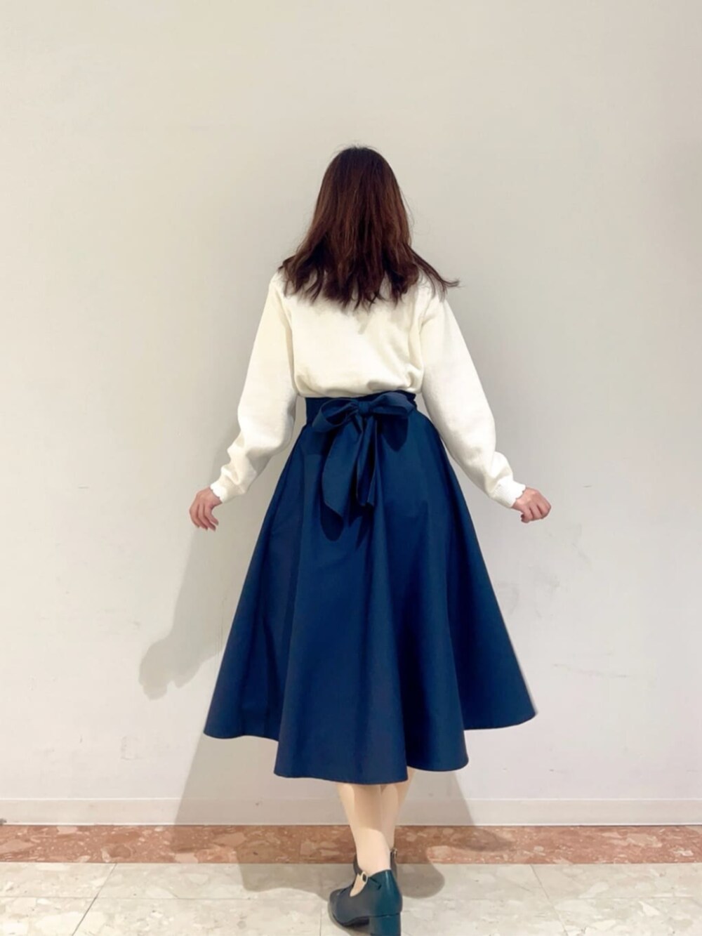 ブルー系のハンドバッグ、ブルー系のパンプス、ホワイト系のニット/セーターを着用したレディースの冬コーディネートの3枚目の写真