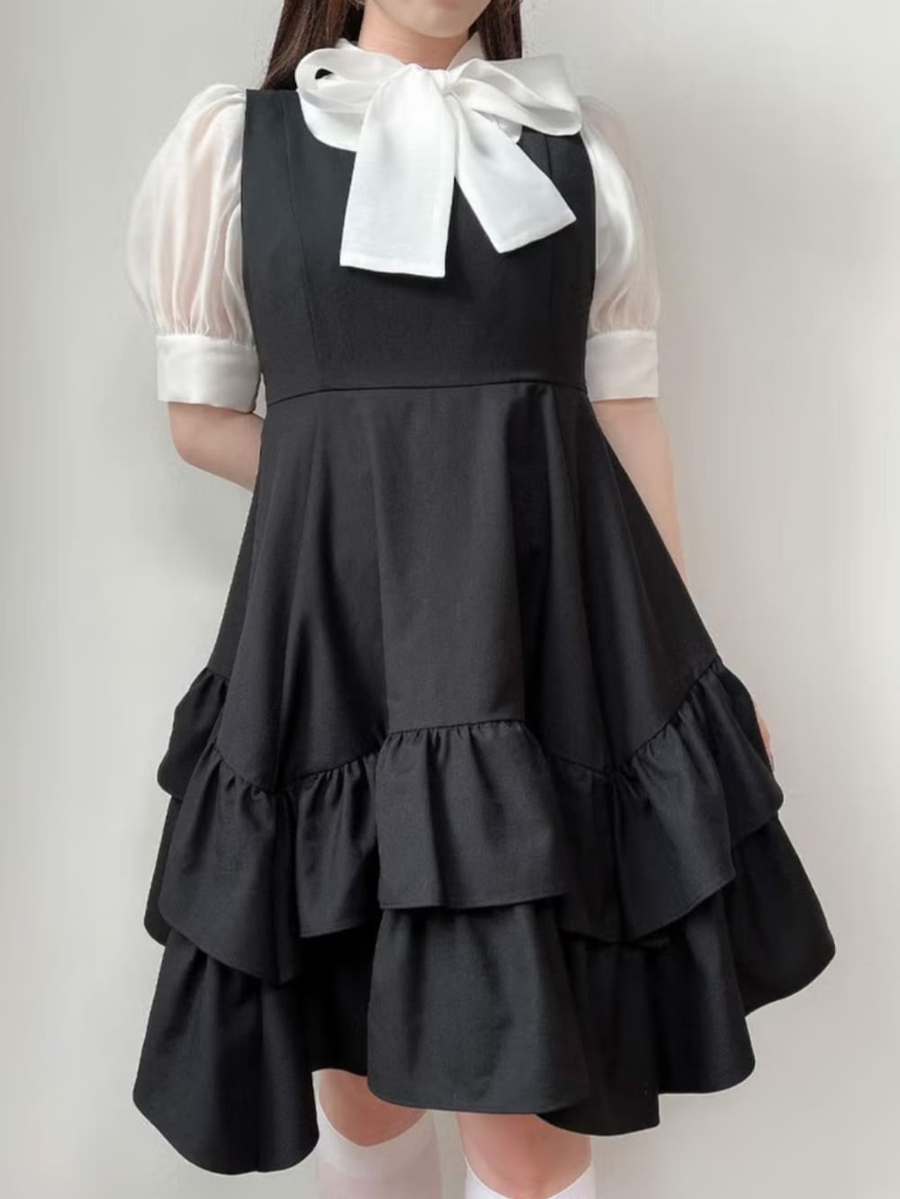 ブラック系のパンプス、ブラック系のジャンパースカート、ホワイト系のシャツ/ブラウスを着用したレディースの夏コーディネートの3枚目の写真