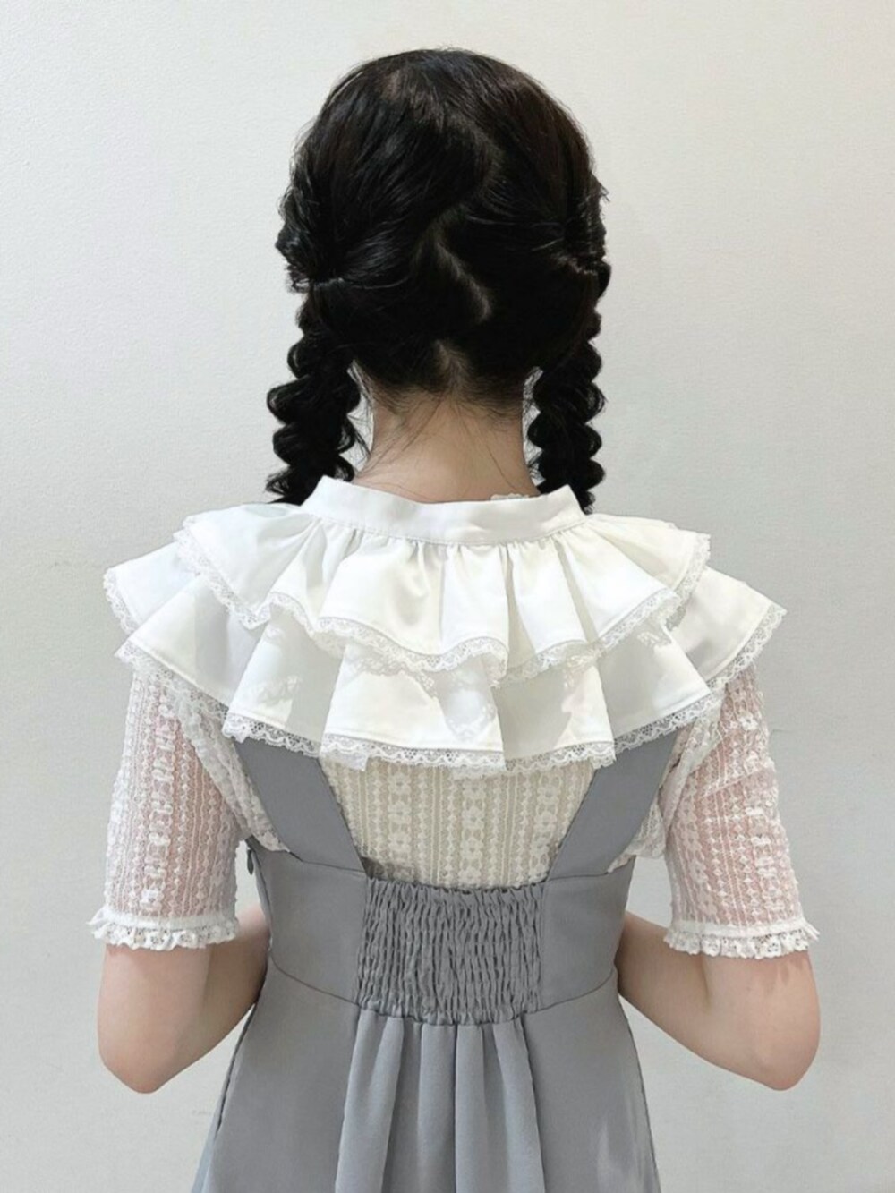 ブラウン系のパンプス、グレー系のジャンパースカート、ホワイト系の付け襟を着用したレディースの春コーディネートの3枚目の写真