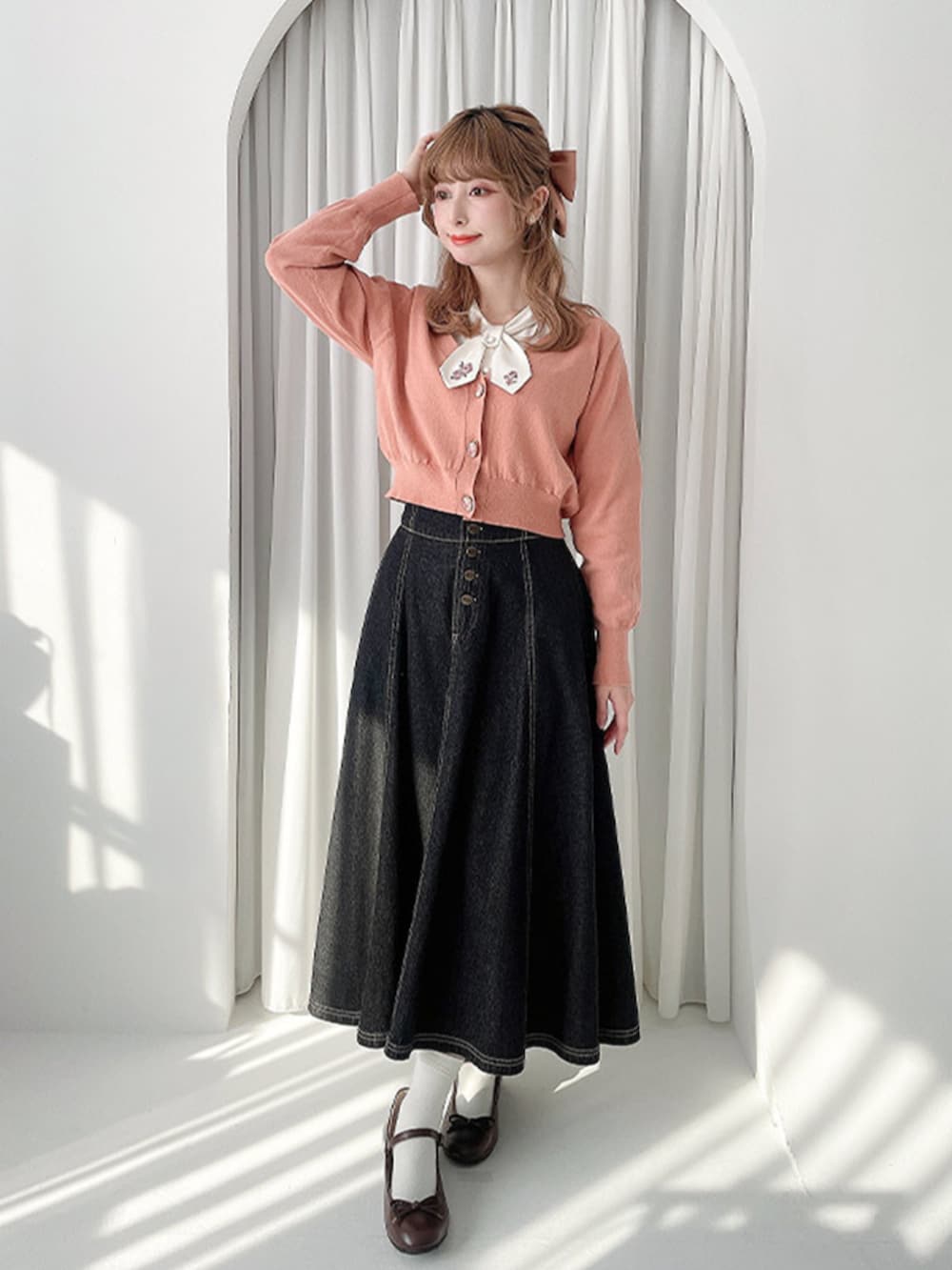ブラック系のデニムスカート、ブラウン系のバレエシューズ、ピンク系のカーディガン/ボレロを着用したレディースの春コーディネートの2枚目の写真