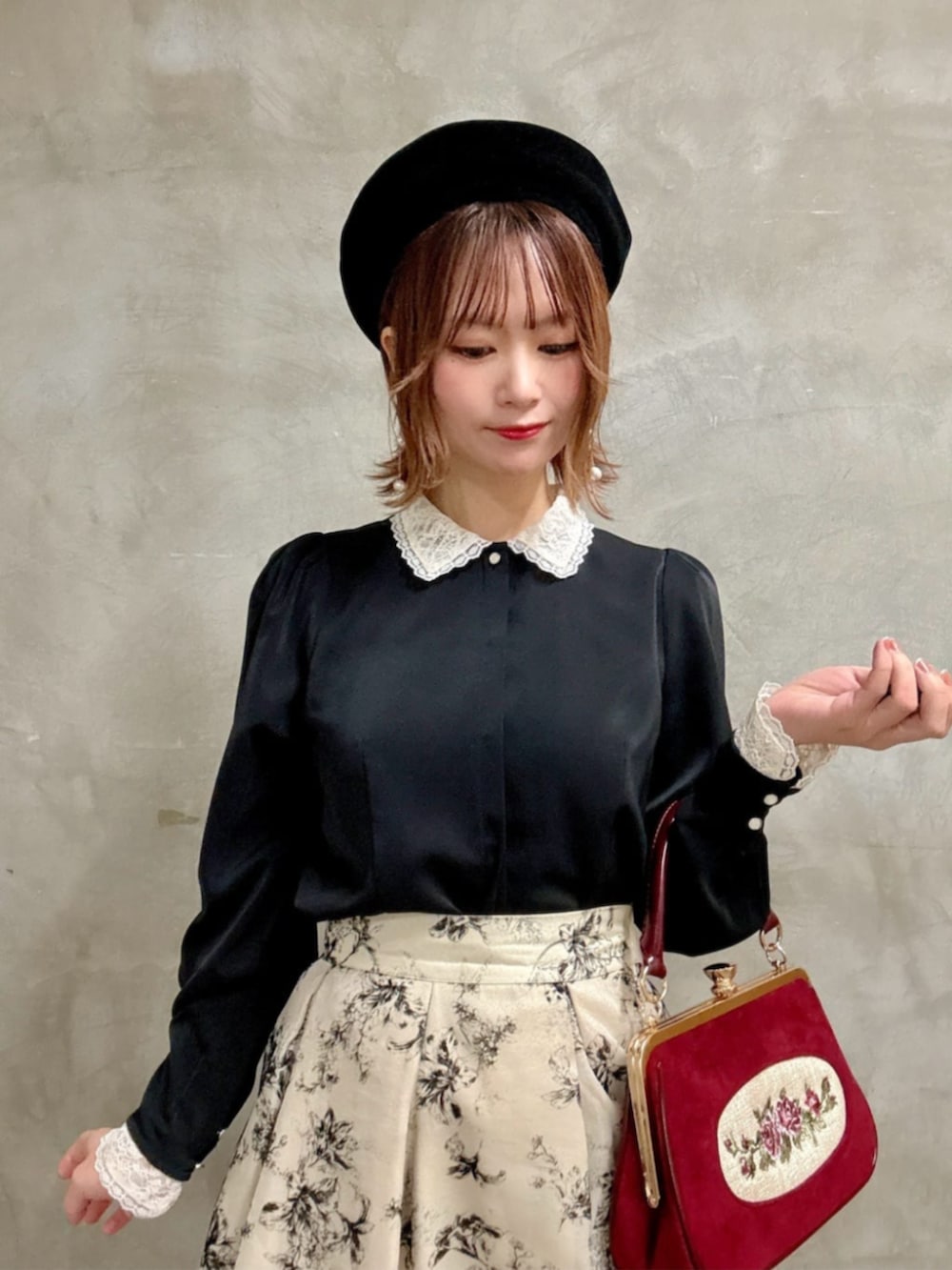 レッド系のハンドバッグ、ブラック系のシャツ/ブラウス、ホワイト系のスカートを着用したレディースの冬コーディネートの2枚目の写真