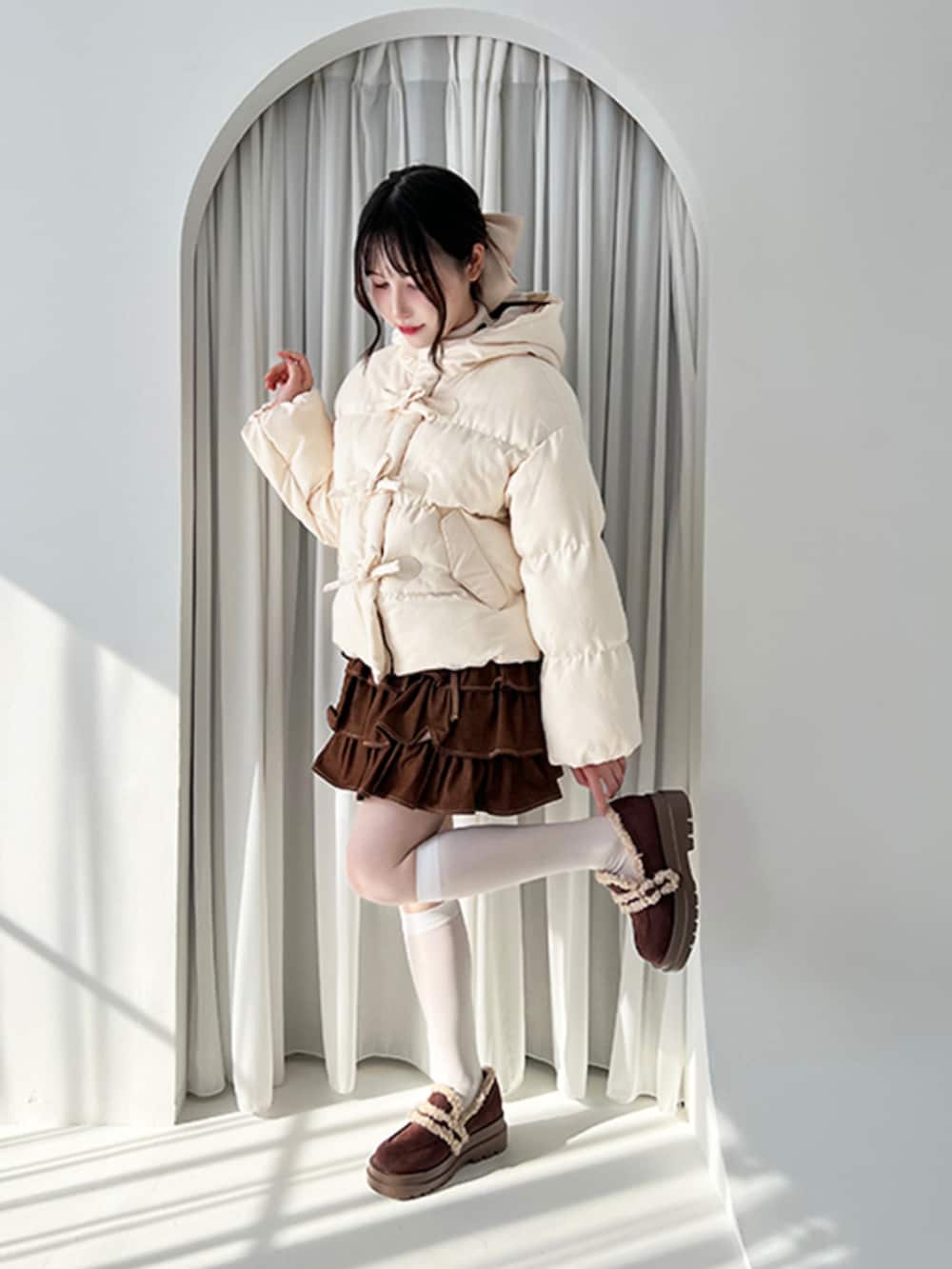 ホワイト系のダウンジャケット/コート、ブラウン系のスカート、ブラウン系のモカシン/デッキシューズを着用したレディースの秋コーディネートの2枚目の写真