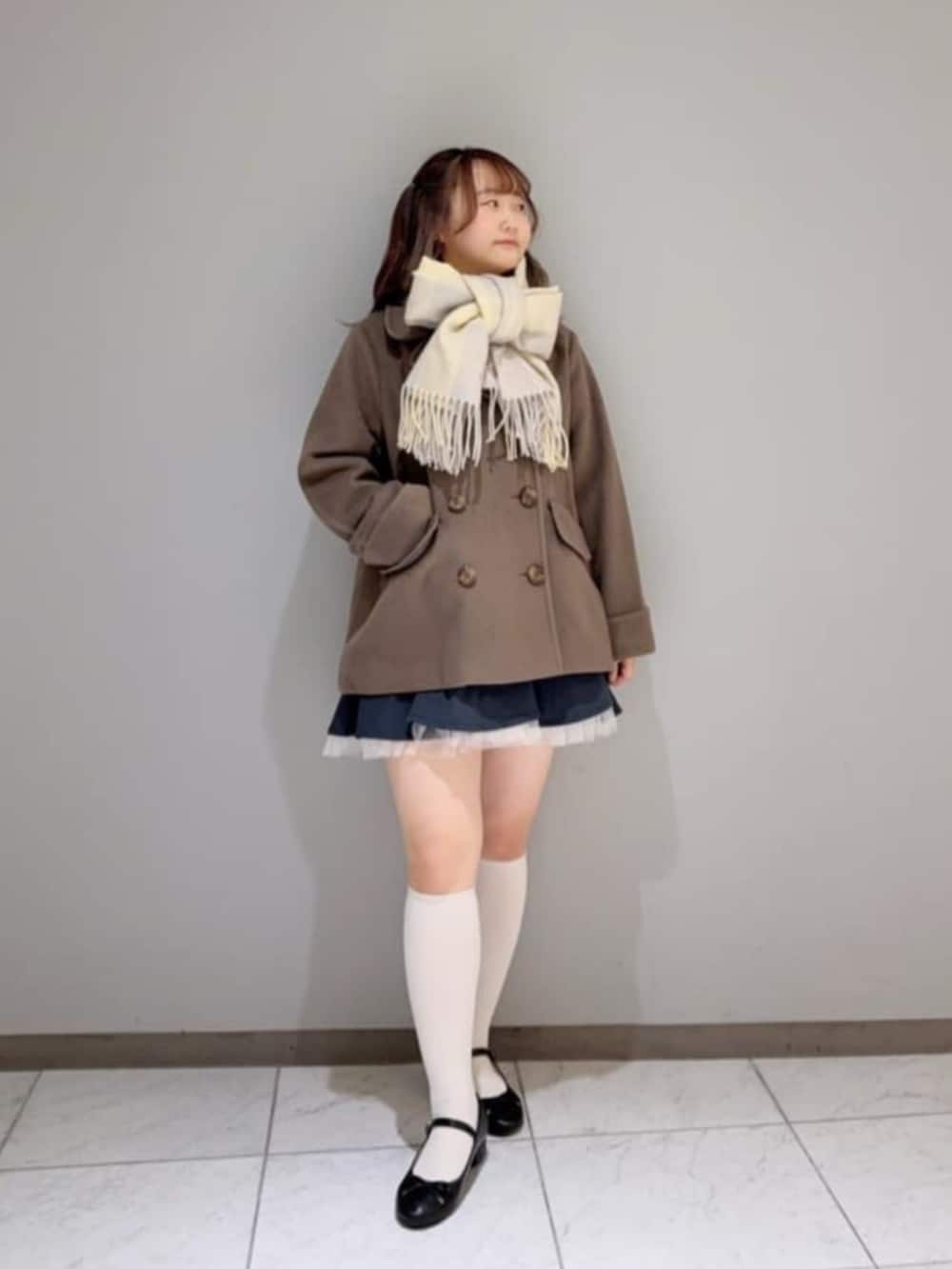 ブラック系のバレエシューズ、ブラウン系のピーコート、ブルー系のスカートを着用したレディースの冬コーディネートの2枚目の写真