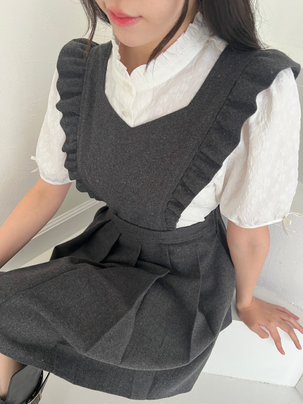 ホワイト系のシャツ/ブラウス、グレー系のジャンパースカート、ブラック系のブーツを着用したレディースの秋コーディネートの5枚目の写真