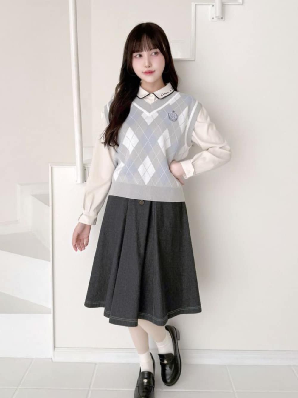 ブラック系のローファー、ブラック系のスカート、グレー系のベストを着用したレディースの冬コーディネートの2枚目の写真